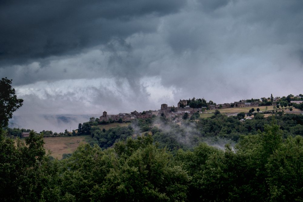 Low clouds over a French village surrounded by green bushes