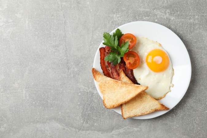 Top view of breakfast for one with eggs, toast, bacon and tomatoes