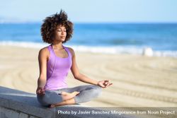 Black woman with afro hairstyle meditating near the sea bEvpG0