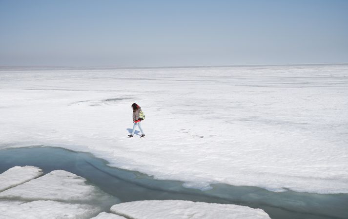 Young adult woman outdoors travelling with backpack in icy lands