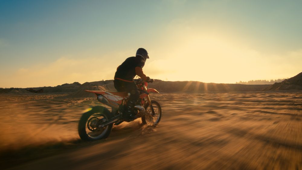 Shot of the Professional Motocross Driver Riding on His FMX Motorcycle on the Extreme Off-Road Terrain Track.