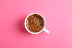 Cup of coffee on color background, space for text