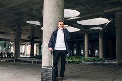 Stylish mature tourist standing outdoors smiling with phone