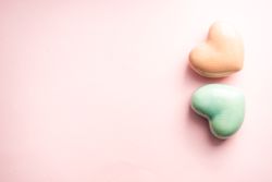 Green and peach heart ornaments on pink background