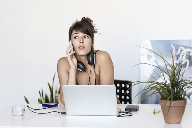 Female listening to message on smartphone at home office
