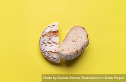Loaf of bread split in half on yellow background bx9nv0
