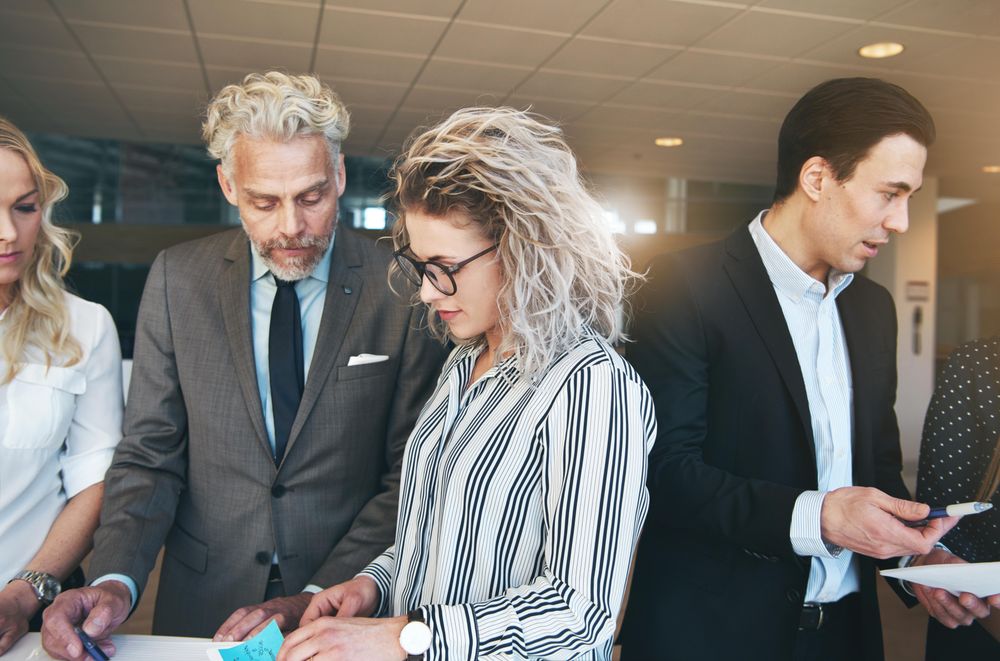 Group of people in business attire standing and discussing work