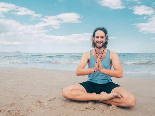 Man training yoga on beach
