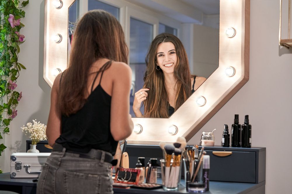 Cheerful woman making up at mirror