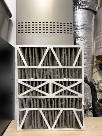 Extremely dirty Furnace air filter being removed from central heating and cooling ventilation system