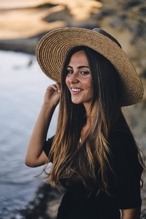 Cheerful woman holding hat in air
