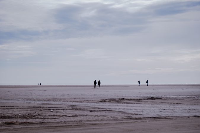 Wide sandy beach with silhouettes of people