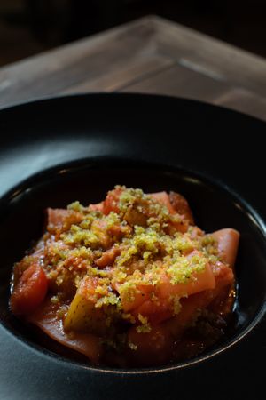 Gourmet paccheri pasta with tomato sauce, vegetables, and crispy breadcrumbs