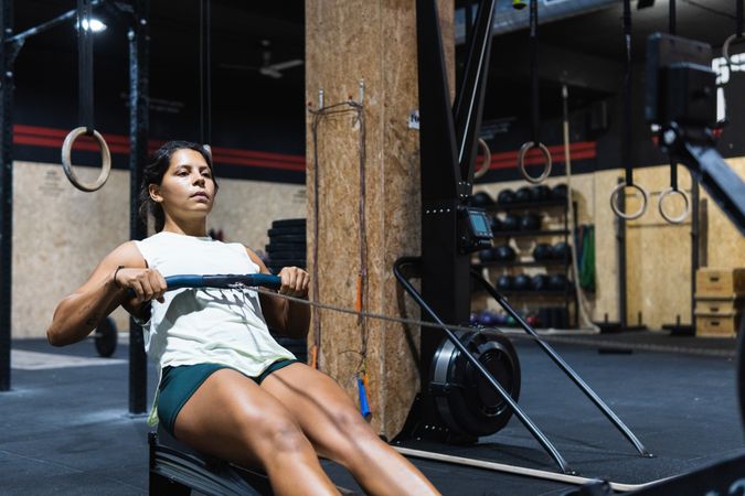 Hispanic sportswoman exercising on rowing machine