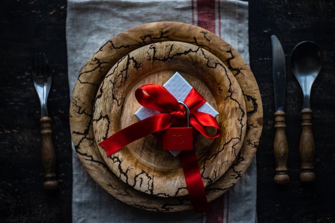 Rustic plate with ribbon wrapped present with padlock and cutlery