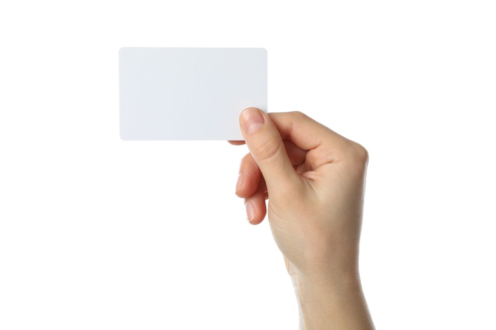 Female hand holding blank business card, isolated on plain background