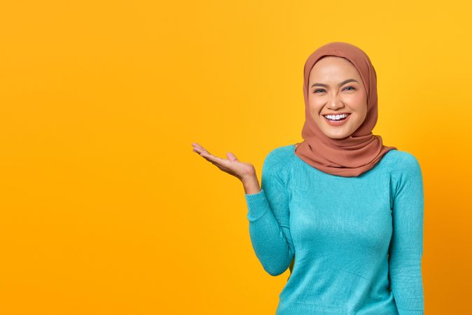 Happy Muslim woman gesturing to copy space