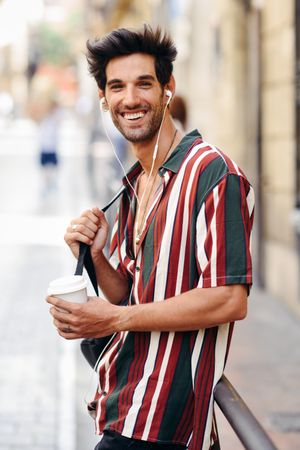 Smiling male in striped shirt standing in the streets of Granada, Spain with coffee
