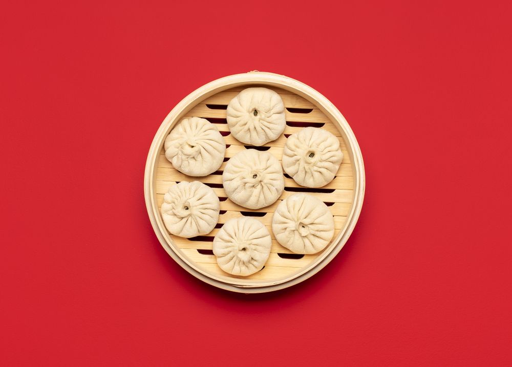 Raw baozi dumplings in a bamboo steamer, top view