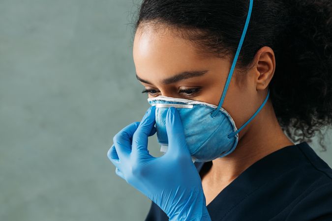 Side view of Black female doctor tightening her protective mask