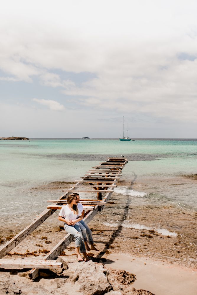 Glad lovers sitting on destroyed pier on seashore