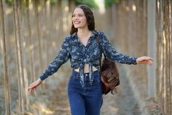 A Happy Young Woman Joyfully Walking Along a Beautiful TreeLined Pathway Surrounded by Nature