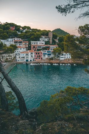 Sailboats on sea water against houses on rocky shore