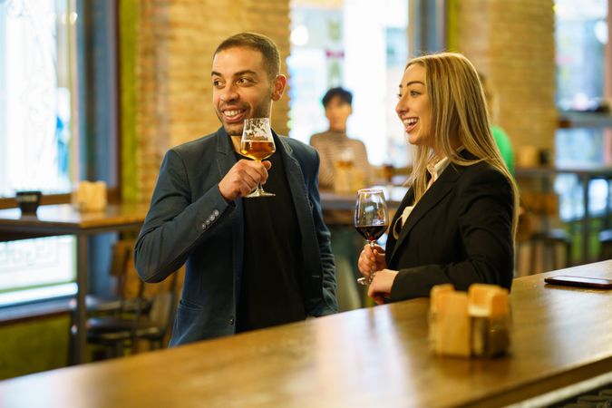 Man and woman smiling at something in the distance while in a bar
