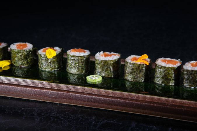 Appetizing sushi rolls with salmon and pepper on tray