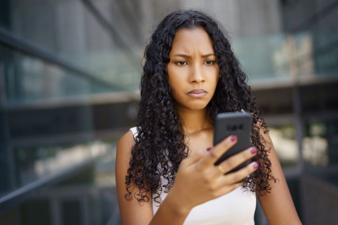A Concerned Woman is Interacting Thoughtfully with Her Smartphone in an Urban Setting