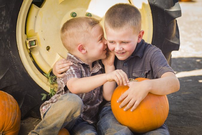 Two Boys Having Fun at the Pumpkin Patch on a Fall Day.