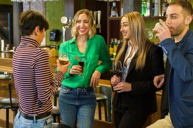 Group of friends socializing with drinks in bar while chatting