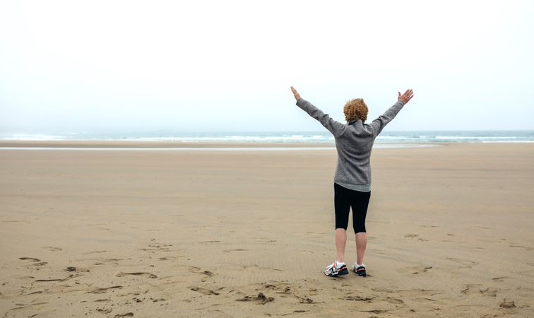 Woman watching the sea with hands up