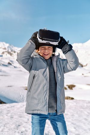 Smiling boy in VR headset in winter mountains