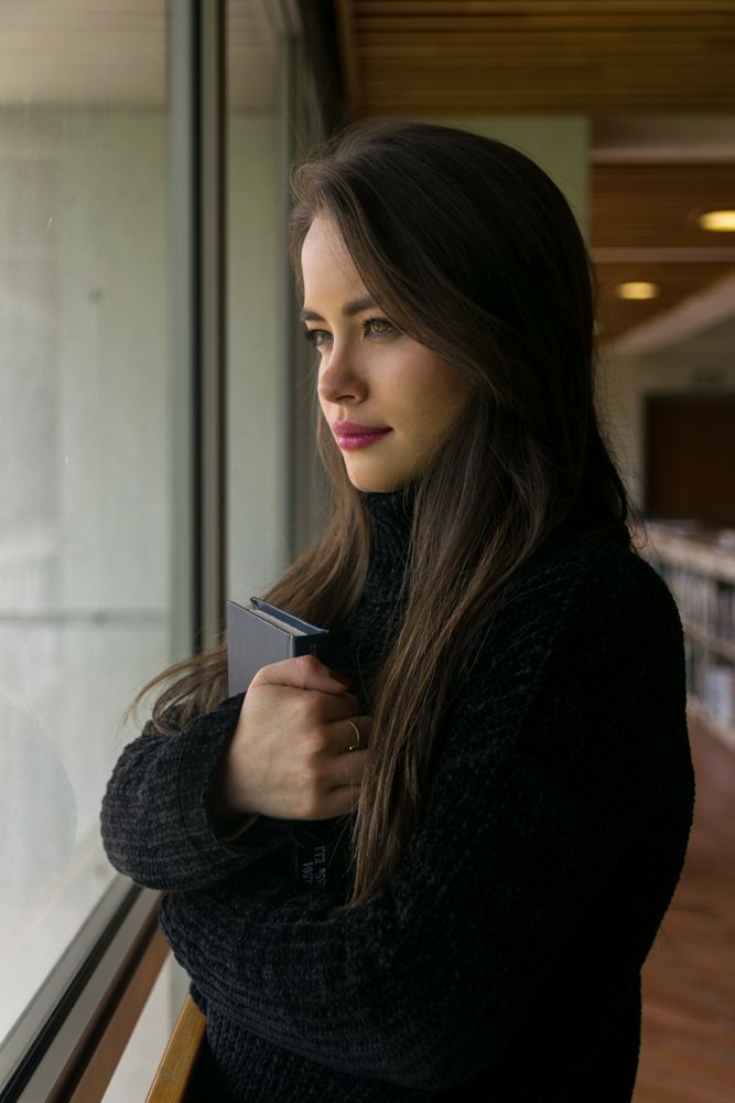 Woman with book looking out window