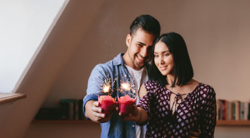 Young couple holding two cupcakes and celebrating their anniversary