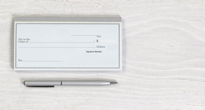 Blank checkbook and silver pen on desktop