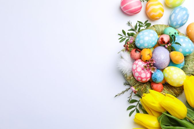 Flat lay composition with nest, Easter eggs, feathers and flowers on color background, space for text