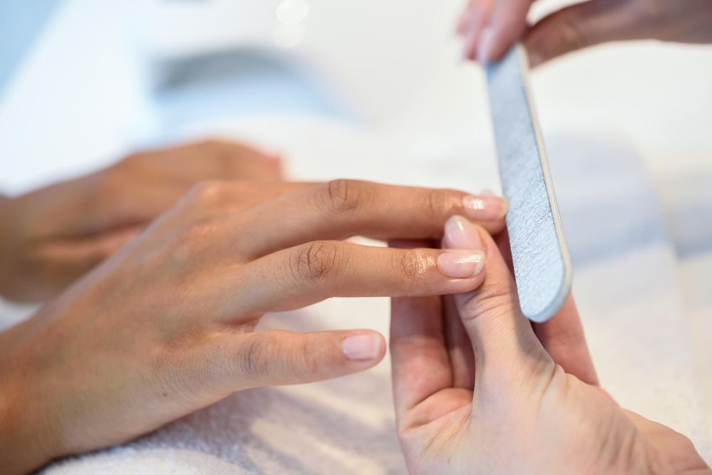 Beautician filing nails of a client
