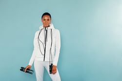 Healthy Black woman in fitness gear with water bottle and jump rope