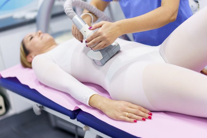Female lying in medical spa having a body treatment for fat loss