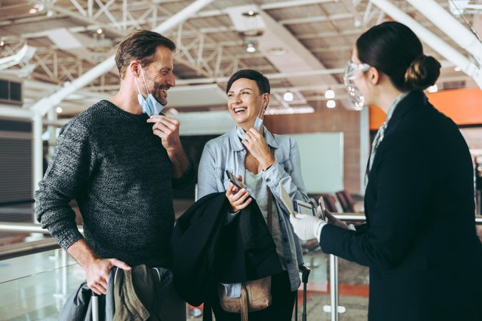 Flight attendant assisting tourist couple at airport check in counter