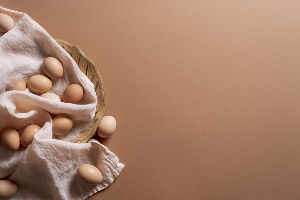 Brown eggs on wooden plate on brown background