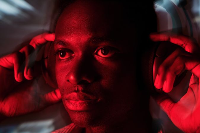 Confident Black man in wireless headphones in red light