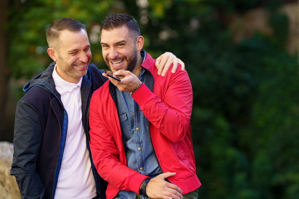 Happy male couple speaking on phone