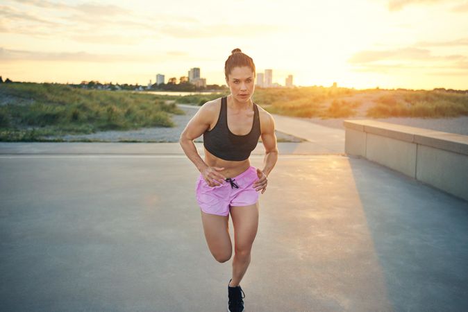 Muscular woman in shots and sports bra running towards the camera