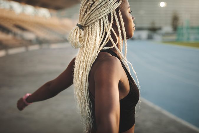 Side view of a woman athlete doing exercise in a track and field stadium