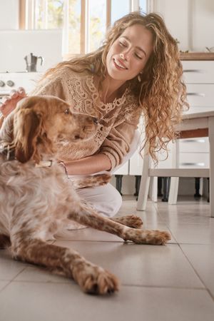 Smiling woman stroking Spaniel in kitchen