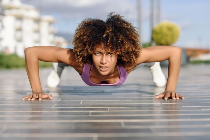 Fit female with afro hairstyle doing planks outside