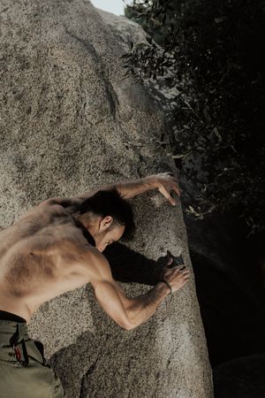 Man practicing rock climbing among large rocks in a forest